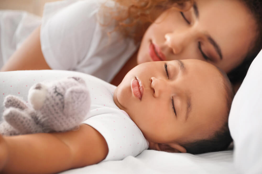 A mum sleeping beside a baby - Funny Advice for New Parents