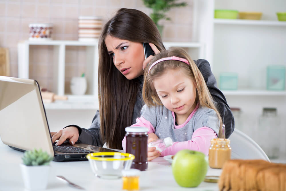 mom multi-tasking with daughter in her lap