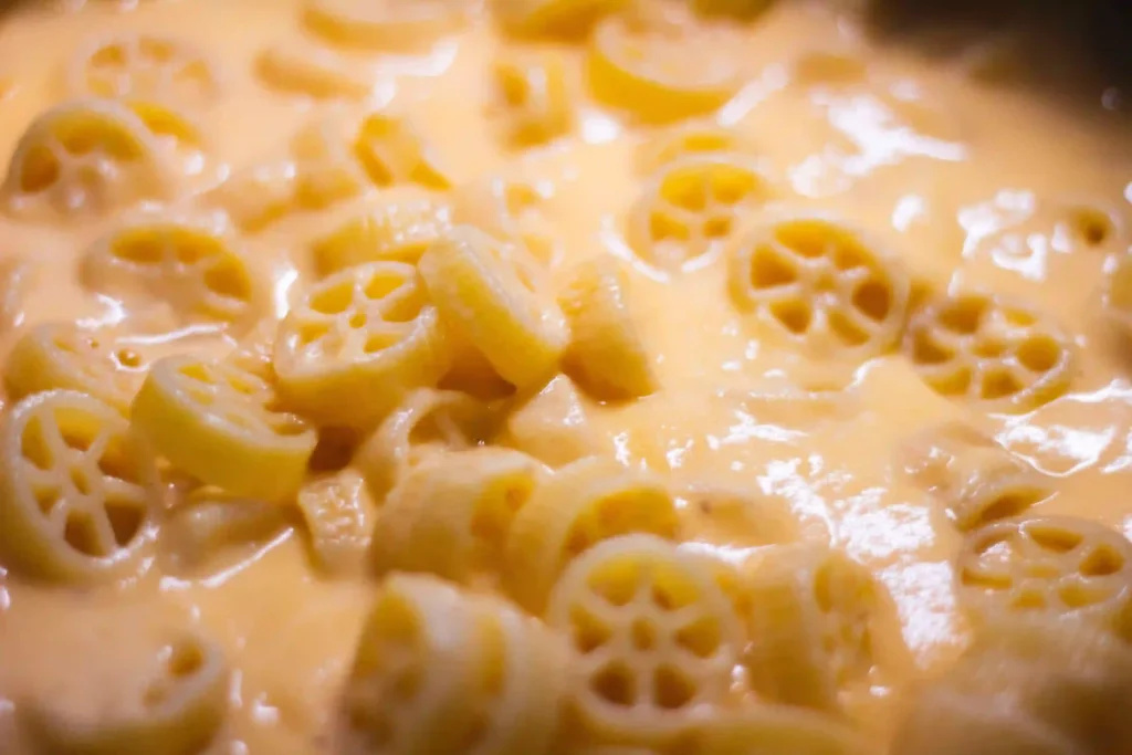 Small pasta coated in cheese sauce, offering a protein-rich and easy-to-grab meal idea for a 10-month-old baby.