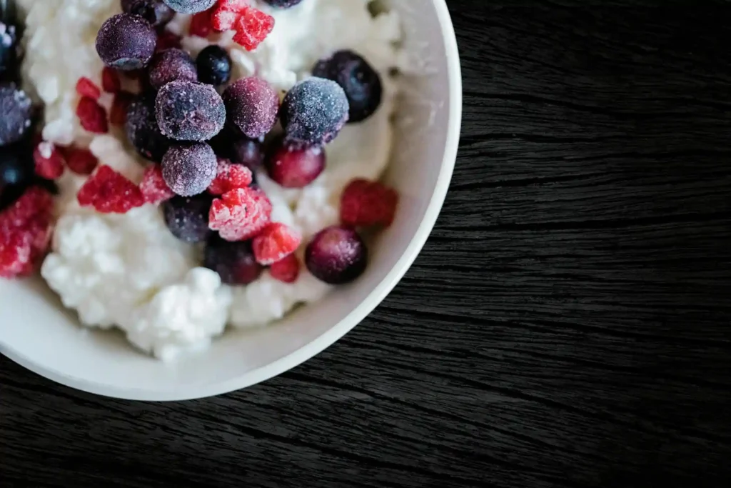 A bowl of full-fat cottage cheese topped with bite-sized pieces of ripe peaches, an ideal protein-packed snack for a 10-month-old.