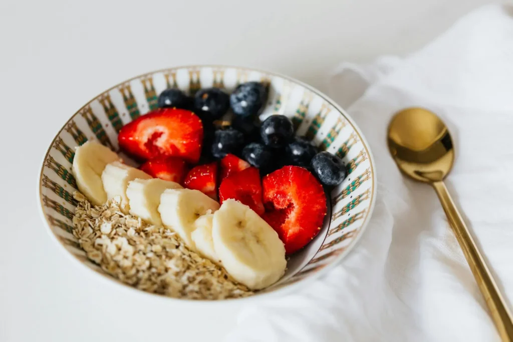 Warm oatmeal mixed with mashed banana and applesauce, served in a baby bowl as a fiber-rich breakfast for a 10-month-old.